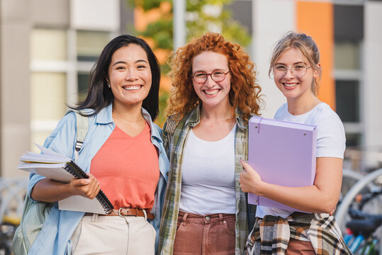 Portrait of diverse group of female college students standing in front of a university building
