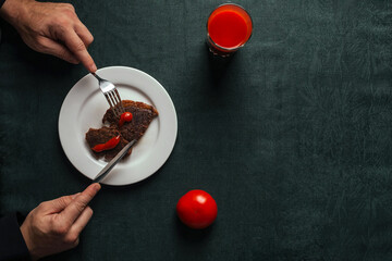 Fototapeta na wymiar man having dinner consisting of delicious grilled beef steak and bright red tomato juice, top view with space for text