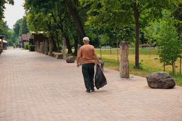 The janitor collects garbage in the park.