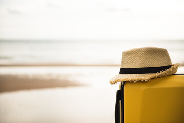 Suitcase with hat on the beach.