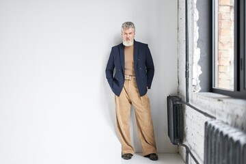 Full length shot of stylish middle aged man in business casual wear looking at camera, putting...