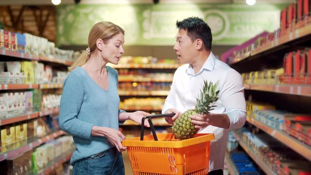 A family couple arguing and quarreling while standing in a supermarket grocery store. The husband is angry with his wife. evil man that a woman bought unnecessary expensive goods spending budget