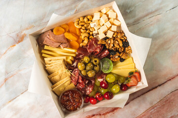 charcuterie box with cheeses, crackers, strawberries, olives, grapes, cherries, pastrami, salami,...