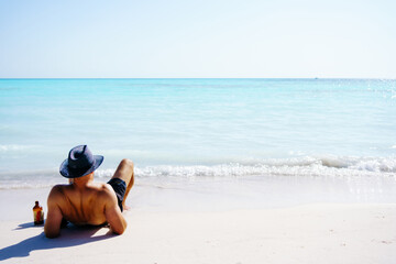 a man with straw hat is on the sand and looks at the sea