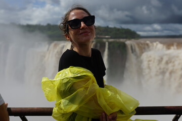 In the photo, a beautiful girl in a white shirt stands against the backdrop of the Iguazu...