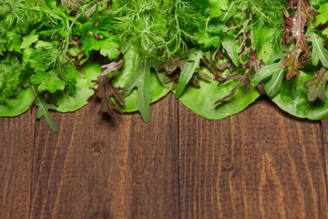 top view of green dill, parsley, salad, herbs and other greens on a dark wooden background, concept of fresh vegetables and healthy food, blank space or copy space for text