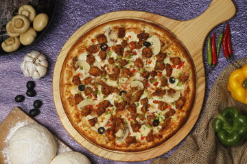 Flatbread pizza garnished with fresh angular on wooden pizza board top view dark stone background