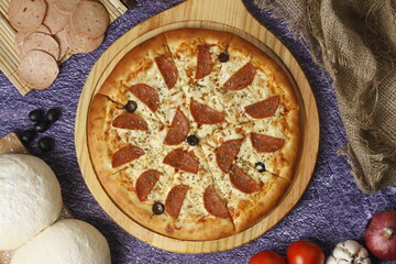 Flatbread pizza garnished with fresh angular on wooden pizza board top view dark stone background