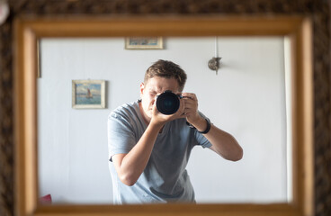 male photographer is taking a selfie photo in an antique mirror, passion photography - obrazy, fototapety, plakaty