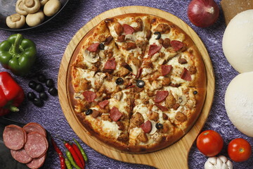 Flatbread pizza garnished with fresh angular on wooden pizza board top view dark stone background