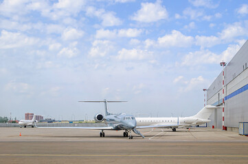 Several business jets on an airport apron. Private or business aviation. Silver and white planes