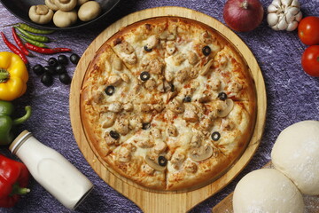 Flatbread pizza garnished with fresh angular on wooden pizza board top view dark stone background