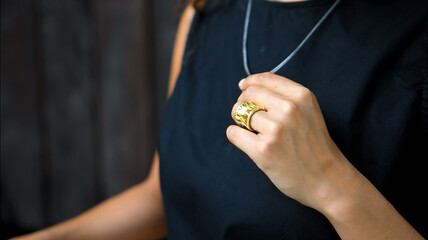 a young European girl sitting in a black dress touching rings and jewelry around her neck