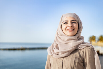 Muslim and modern woman smiling on the beach with hope and happiness