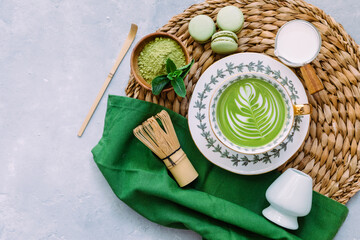 Matcha green latte, matcha powder, bamboo whisk and spoon on a blue background. Japanese tea...
