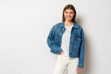 Fototapeta na wymiar Woman with fair hair dressed in white t-shirt, denim jacket and jeans, holding hand in pocket