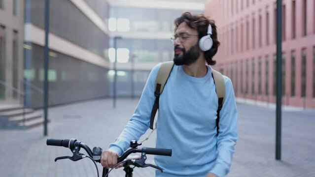 Happy young entrepreneur worker man in headphones listening to music while dancing after working day outdoors - Happiness and success concept