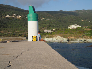 homme dans un port assis au pied du phare - Corse