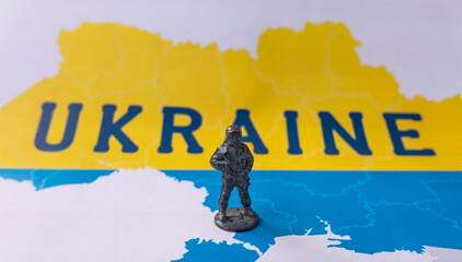 Metal figurine of a soldier on the background of the map of Ukraine.
