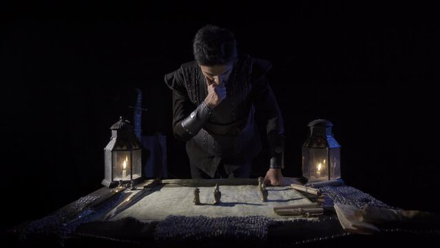 The commander trying to direct the war on the map.
War preparation in historical times. Armored, protective clothing. Cloak. Map and chess pieces standing on it. Candlelight and sword. Historical reen