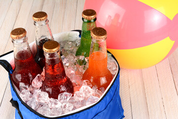 High angle view of a cooler filled with ice and a variety of soda bottles on a white wood...