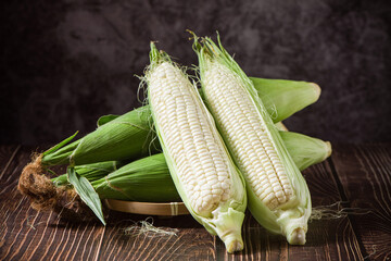 sweet white corn cobs on wooden table