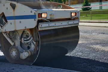 Road roller compactor at work being use on a renewal asphalt project. Compacting the blacktop layer on a street.