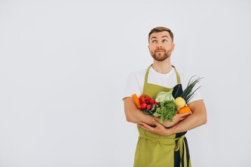 Happy man holding many different fresh vegetables on white background