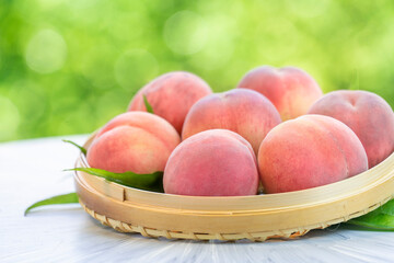 Pink Peach fruit with leaf on blur garden background, Fresh Sweet Peach on wooden basket over natural farm background.