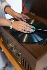 details such as placing music on a record player with vintage wooden design, player with acetate disc, old objects, hands
