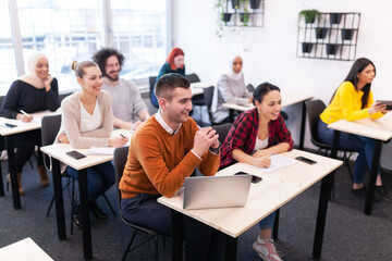 Multi ethnic students listening to a lecturer in a classroom. Smart young people study at a college.