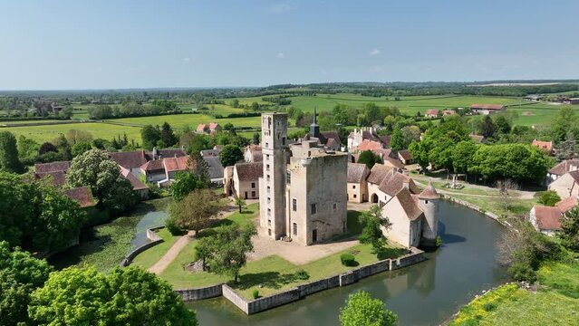 Aerial panning view of Sagonne castle in France with inner complex surrounded by an outer wall strengthened by circular towers, moat filled with water