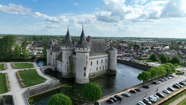 Circling around Sully sur Loire fairytale French water castle with circular towers, gate house from the manicured garden on a spring afternoon