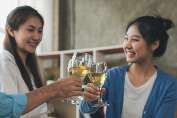 Group of young Asians clinking white wine glasses, startup company parties, New Year's parties, annual company parties, alcoholic beverages. Company employee party catering ideas, celebrations.