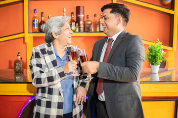 Happy indian business people holding glass of wine and champagne in hand, Young man and senior woman corporate party to celebrate company success.