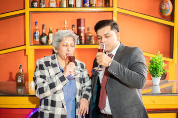Happy indian business people holding glass of wine and champagne in hand, Young man and senior woman corporate party to celebrate company success.