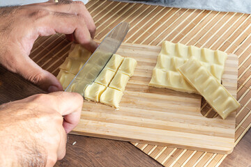 man cutting pieces of white chocolate on wooden cutting board