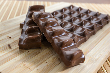 chocolate pieces, bar and slices over wooden cutting board and bamboo table