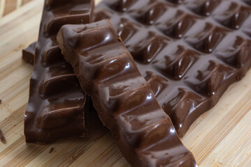 chocolate pieces, bar and slices over wooden cutting board and bamboo table