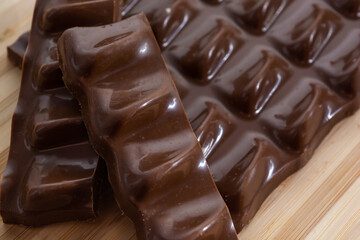 chocolate pieces, bar and slices over wooden cutting board and bamboo table