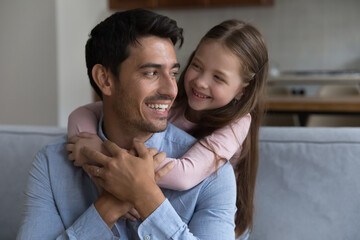 Caring dad enjoy warm moments of tenderness with little daughter. Preschool girl piggyback loving daddy sit together on sofa spend leisure at home. Family ties, happy fathers day celebration concept