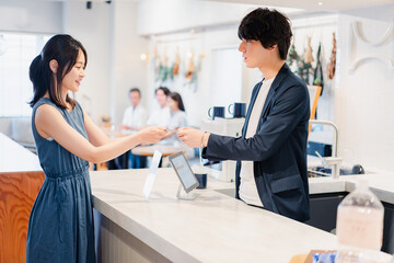 Fototapeta premium レジでクレジットカード決済をする若い女性