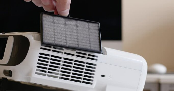 Hand of man removes dust filter from modern air conditioner to replace for new. Householder opens lid of appliance showing remaining dust closeup