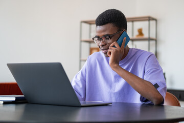 Black businessman talk on the phone, laptop on desk in office room