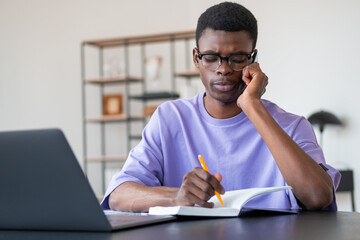 African businessman talk on the phone, take note in notebook on desk