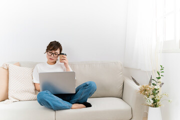 家のソファでパソコンを使う日本人女性（VDT症候群）
