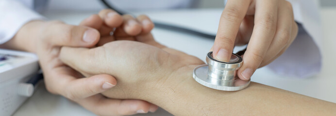 Female doctor uses a heart rate monitor of a male patient to take an initial pulse, Early health...
