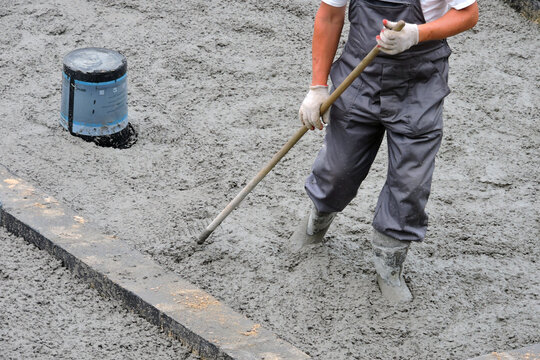 A builder levelling and spreading concrete with a rake