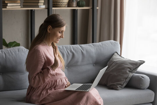 Young Pregnant Woman Use Laptop Makes Video Call Seated On Sofa At Home. Expectant Mother Make Videocall Start Communication To Obstetrician, Receive Consultation On-line. Tech, Telemedicine Concept