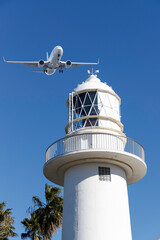 旅、青空を背景に白い灯台の上を通過する旅客機 - obrazy, fototapety, plakaty